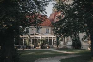 an exterior view of a white house with trees at Dwór Sieraków in Sieraków