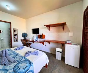 a bedroom with a bed and a desk with a computer at Pousada Areias de Flecheiras in Flecheiras