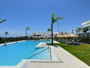 a large swimming pool with chairs and umbrellas at Alcazaba Lagoon & Private Beach Costa del Sol 1903 in Estepona