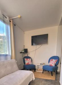 a bedroom with two blue chairs and a flat screen tv at Casa Vereda do Calhau - With barbecue in Campanário
