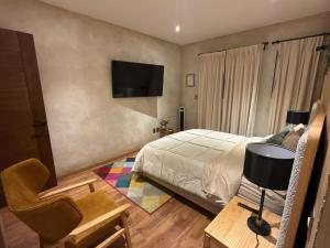a bedroom with a bed and a chair and a television at Grecia en ValQuirico in Santeagueda