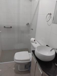 a white bathroom with a toilet and a sink at 502 edificio premieri in Piratuba +10 photos