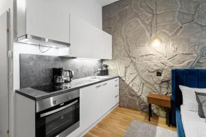 a kitchen with white cabinets and a stone wall at U1 Metro Nearby - 1-BR - fast Wi-Fi in Vienna