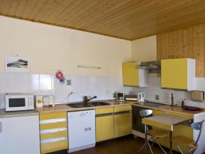 a kitchen with yellow and white cabinets and a sink at Apartment mit Pool und überdachtem Balkon by Interhome in Beerfelden