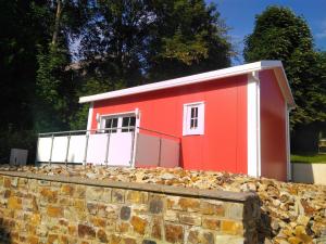 a red and white shed behind a stone wall at Holiday Home Tiny Haus Westerwald by Interhome in Bad Marienberg