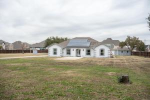 a white house with a solar roof on a yard at DFW Spacious Cozy Modern Villa in Grand Prairie