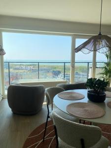 a room with a table and chairs and a large window at Joy at sea in Bredene-aan-Zee