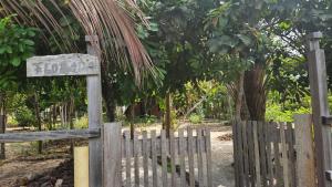 a wooden fence with a sign in front of some trees at Florada in Ilha do Maiandeua +1 photo