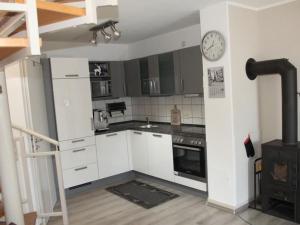 a kitchen with white cabinets and a clock on the wall at Holiday Home Adele - Allergiker geeignet by Interhome in Zandt