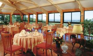 ein Esszimmer mit Tischen und Stühlen und Fenstern in der Unterkunft Résidence Les Hauts de Marquay in Marquay