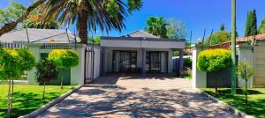 a house with a gate and a palm tree at 27 on Donaldbain in Welkom