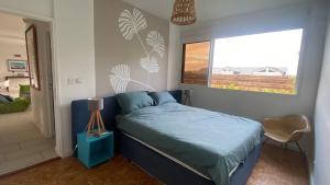 a bedroom with a blue bed and a window at Villa design et piscine Le Gosier in Le Gosier