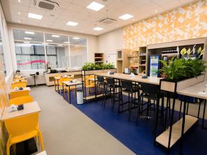 a dining room with yellow chairs and tables and a cafeteria at IBIS BUDGET CAPAO Bonito in Capão Bonito