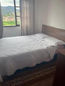 a bed in a bedroom with a window at Maxi conforto e vista para o Itacolomi in Ouro Preto
