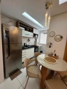 a kitchen with a table and a stainless steel refrigerator at Flor da Amazônia 1 Belém - PA in Ananindeua