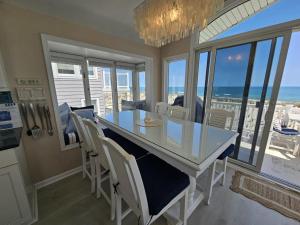 a dining room with a table and chairs and the ocean at Second Floor Oceanfront Unit in Brant Beach