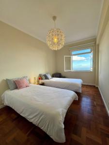 two beds in a room with a chandelier at Santos Living Rentals in Funchal