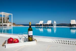 una bottiglia di vino e bicchieri accanto alla piscina di Villa Irini a Naoussa