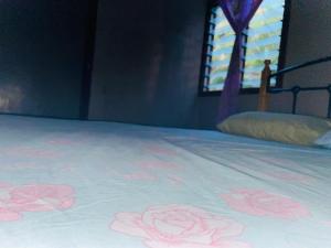 a bed with pink roses on it with a window at Nukuasiga in Soso