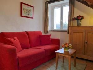 a red couch in a living room with a table at by Interhome in Louhossoa