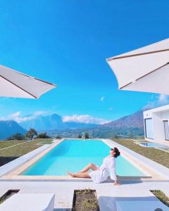 a woman sitting on the edge of a swimming pool at Pinggan Plato in Baturaja