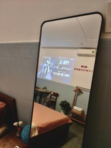 a mirror in a room with a tv and a bed at MOJA HOUSE l Homestay Huế in Thôn Dương Xuân Hạ