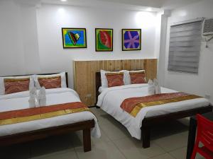 ein Schlafzimmer mit zwei Betten und Gemälden an der Wand in der Unterkunft D'Builders Rooms Hotel in Sampong + 10 Fotos