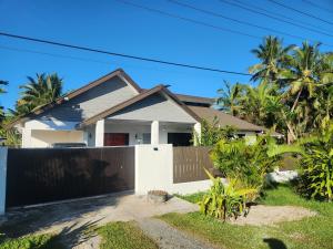 a house with a fence and palm trees at Villa 820 in Pacific Harbour
