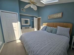a bedroom with a bed with blue walls and a ceiling fan at Second Floor Oceanfront Unit in Brant Beach