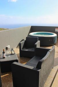 a patio with a hot tub and chairs and a table at Ocean Hill House by Rentery Madeira in Santa Cruz