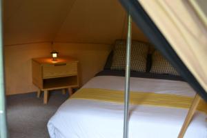 a small bedroom with a bed and a night stand at Cocuyo Glamping in San Agustín Etla