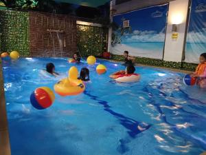 Eine Gruppe Kinder spielt mit aufblasbaren Gegenständen in einem Schwimmbecken. in der Unterkunft D'Builders Rooms Hotel in Sampong