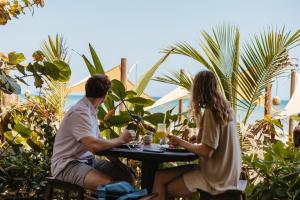 a man and woman sitting at a table with drinks at Bohemia Beach Tayrona in Guachaca +18 photos