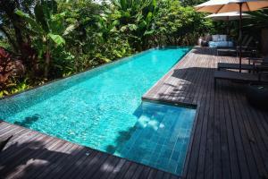 ein Swimmingpool neben einer Holzterrasse mit Sonnenschirm in der Unterkunft palay in Cabulihan