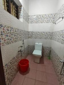 a bathroom with a toilet and a red bucket at Cozy Nest in Pūvār