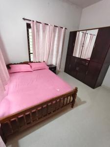 a bedroom with a bed with pink sheets and a dresser at Cozy Nest in Pūvār