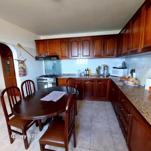 a kitchen with wooden cabinets and a table with chairs at Casa do Arco in Arco da Calheta
