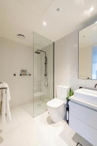 a white bathroom with a shower and a toilet and a sink at Domain House Executive in Melbourne