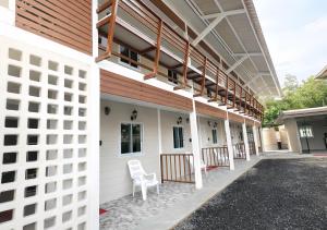 a white building with a white chair on the side at MBB House in Thalang