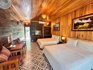 a bedroom with two beds and a table and a couch at Peaceful Garden Tam Cốc in Ninh Binh
