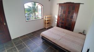 a bedroom with a bed and a cabinet and a window at Casa do Sargento in Saquarema