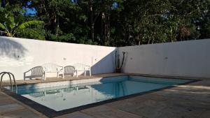 a swimming pool with chairs next to a white wall at Casa do Sargento in Saquarema