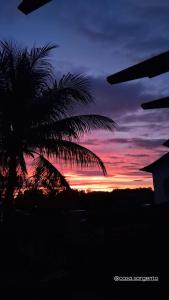 a palm tree in front of a sunset at Casa do Sargento in Saquarema
