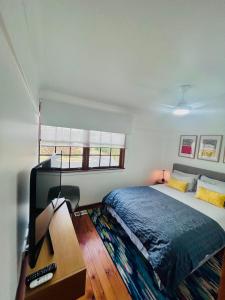 a bedroom with a bed and a desk with a tv at Watson Street Cottage in Albury