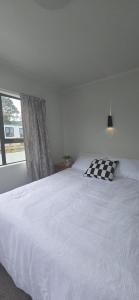 a bedroom with a white bed with a checkered pillow at Beachfront Bliss in Snells Beach