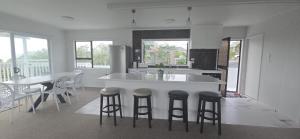 a kitchen with a island with stools and a table at Beachfront Bliss in Snells Beach