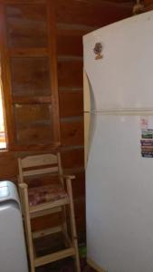 a kitchen with a white refrigerator and a stool at Cabaña Lo de VIVI in Casa Grande +10 photos