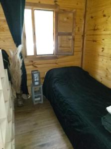 a bedroom with a bed in a wooden cabin at Cabaña Lo de VIVI in Casa Grande