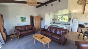 a living room with brown leather furniture and a kitchen at Turanga Heights in Gisborne