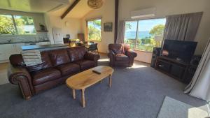 a living room with a leather couch and a coffee table at Turanga Heights in Gisborne